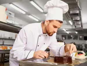 Un patissier qui fait les finissions d'un dessert