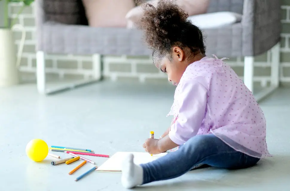 Les petits Afro-Américains aiment écrire ou dessiner avec des crayons de couleur sur un cahier